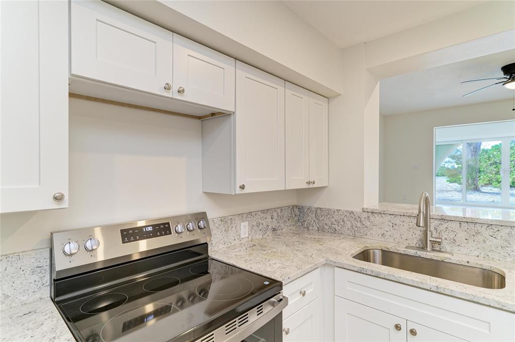 101 73rd Street, Unit 3 Holmes Beach, FL 34217 - Photo 19 of 53 a kitchen with granite countertop a sink cabinets and stainless steel appliances