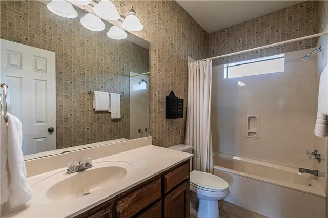 a bathroom with a sink a toilet a mirror and shower