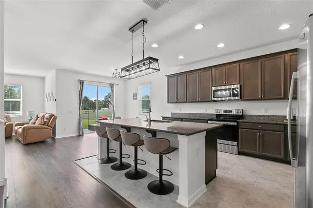 a kitchen with stainless steel appliances granite countertop a table chairs stove and refrigerator