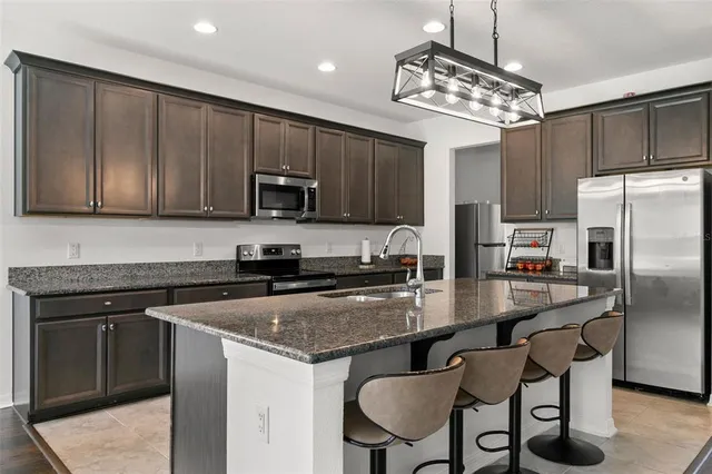 a kitchen with kitchen island granite countertop a sink cabinets stainless steel appliances and a counter top space