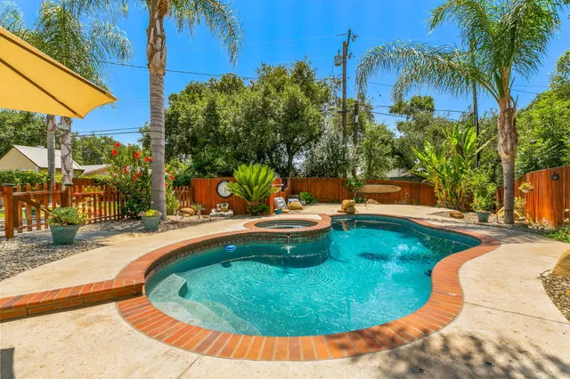 a view of a swimming pool with a patio and a yard