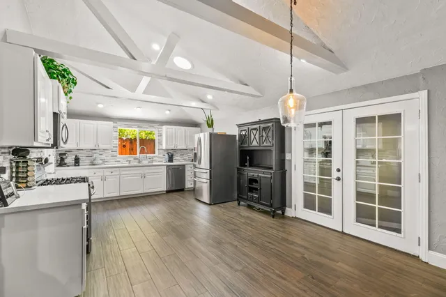 a kitchen with stainless steel appliances kitchen island granite countertop a refrigerator a oven a stove and a wooden floors