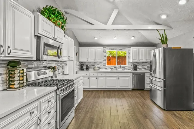 a large kitchen with stainless steel appliances granite countertop a stove a sink dishwasher and a refrigerator