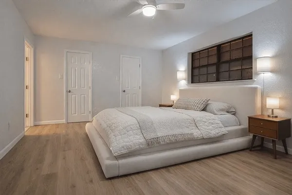a bedroom with a bed a dresser and a potted plant