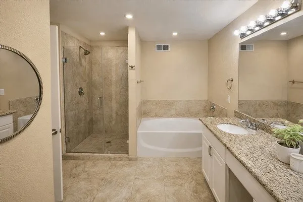 a bathroom with a granite countertop bathtub shower sink and mirror