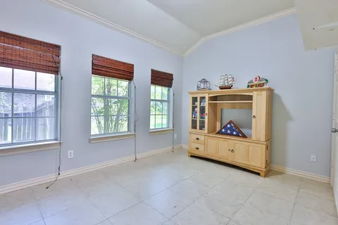 a view of an empty room with window and cabinet area