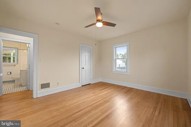 a view of empty room with wooden floor and fan