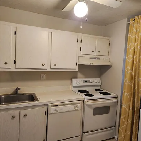 a kitchen with granite countertop white cabinets and white appliances