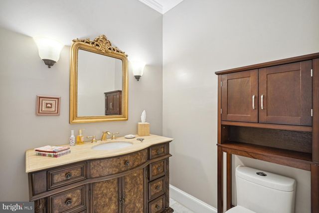 a bathroom with a granite countertop sink toilet a mirror and next to a window