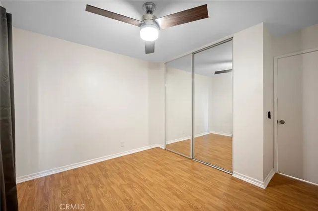 a view of empty room with wooden floor and fan