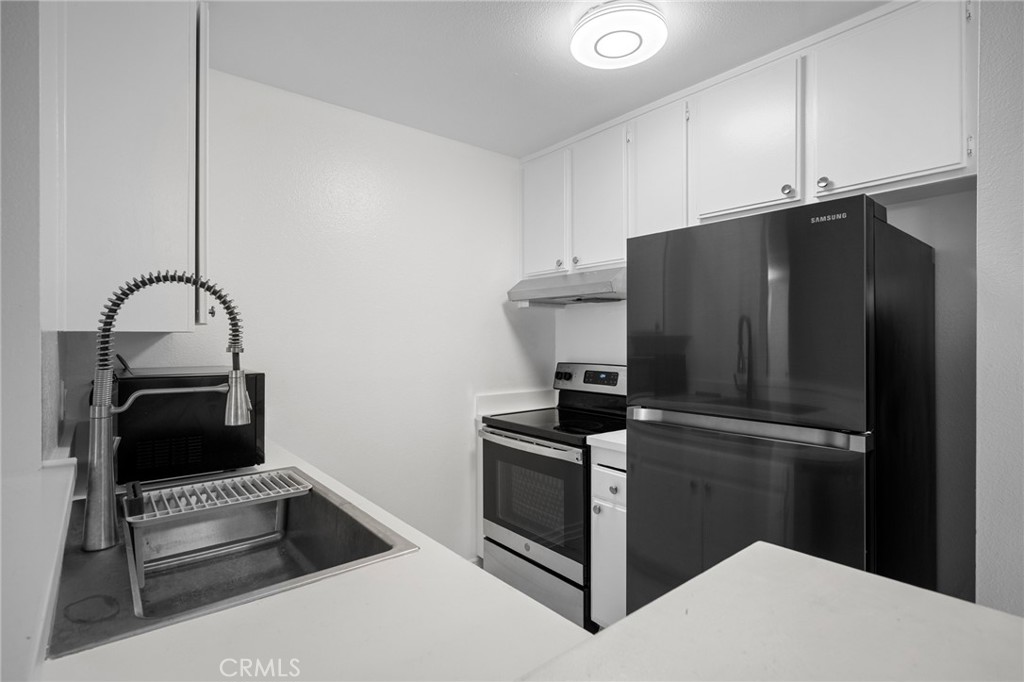 15425 Sherman Way, Unit 107A Van Nuys, CA 91406 - Photo 9 of 23 a kitchen with a refrigerator and cabinets