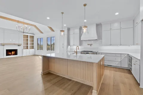 a large white kitchen with stainless steel appliances kitchen island a sink dishwasher a stove and a refrigerator with wooden floor