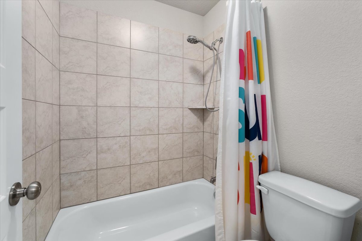 5408 Vanner Path Georgetown, TX 78626 - Photo 27 of 34 Bathroom featuring a shower-tub combination, tiled shower surround with an integrated niche, handheld showerhead, and a white toilet