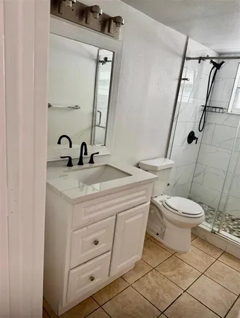 a bathroom with a granite countertop toilet sink and mirror
