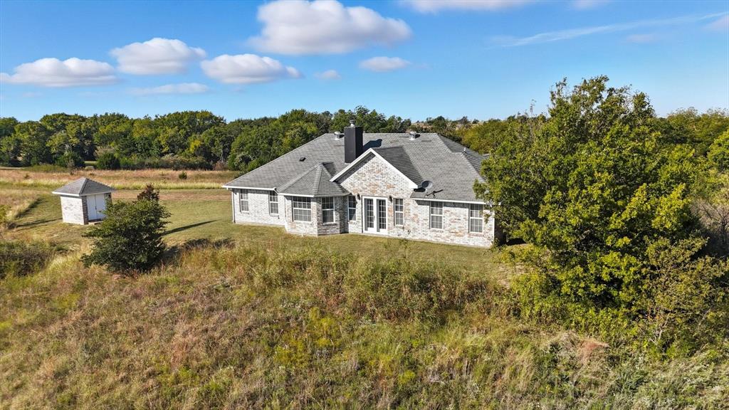 2296 Old Decatur Road Decatur, TX 76234 - Photo 30 of 39 Back of property with stone siding, a chimney, a yard, and a wooded view