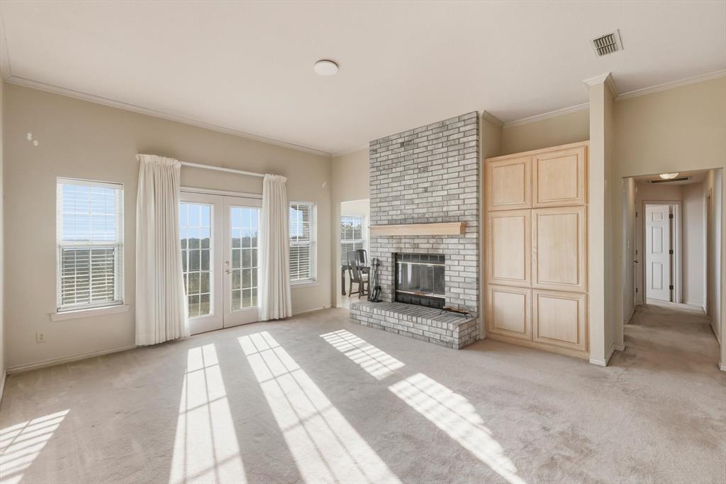 2296 Old Decatur Road Decatur, TX 76234 - Photo 8 of 39 Unfurnished living room featuring french doors, crown molding, light carpet, and a brick fireplace