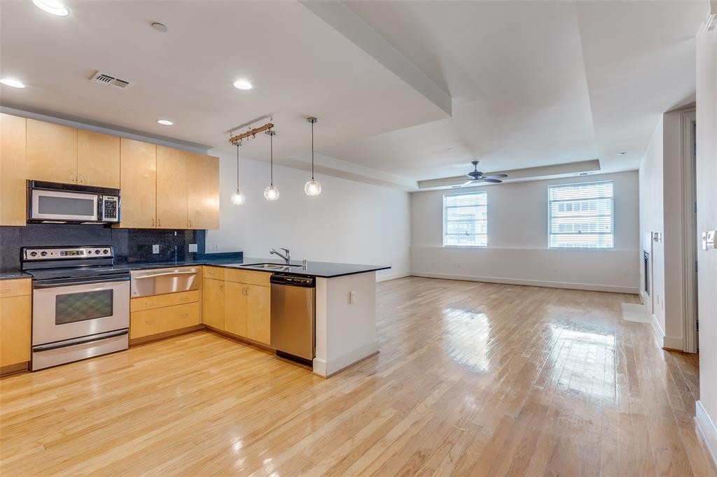 a large kitchen with stainless steel appliances granite countertop a stove and a wooden floors