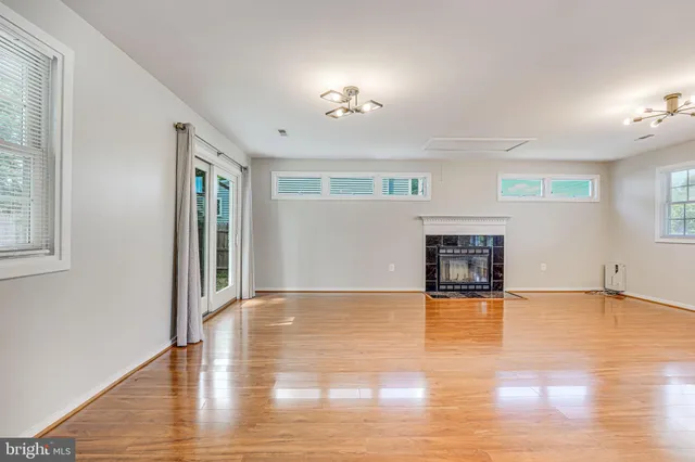 a view of an empty room with window and wooden floor