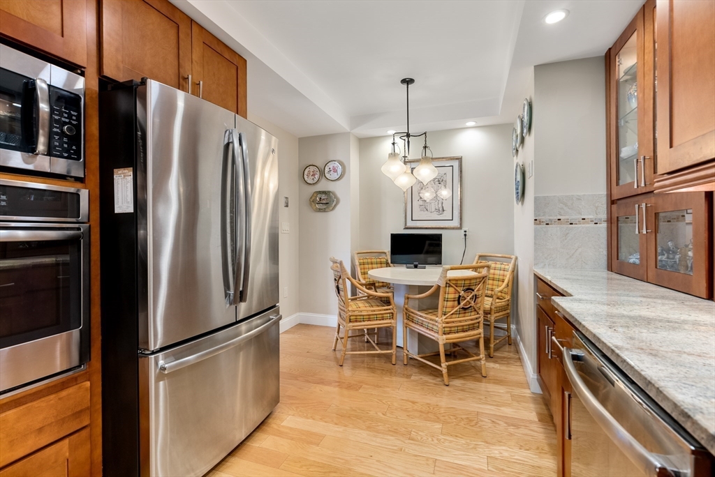 79 Florence Street, Unit 508S Newton, MA 02467 - Photo 4 of 20 a kitchen with stainless steel appliances granite countertop a refrigerator a stove a sink a dining table and chairs with wooden floor