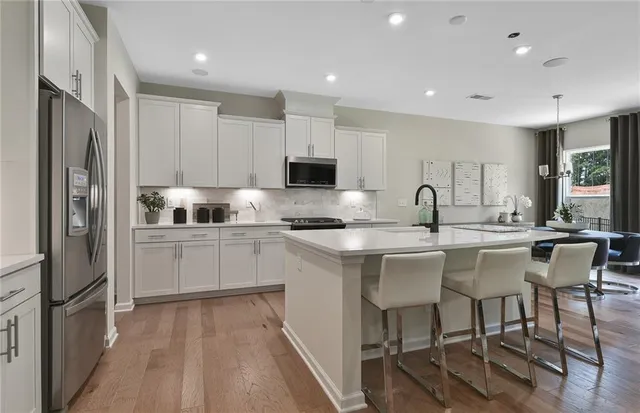 a kitchen with stainless steel appliances granite countertop a stove a sink a microwave a refrigerator and white cabinets