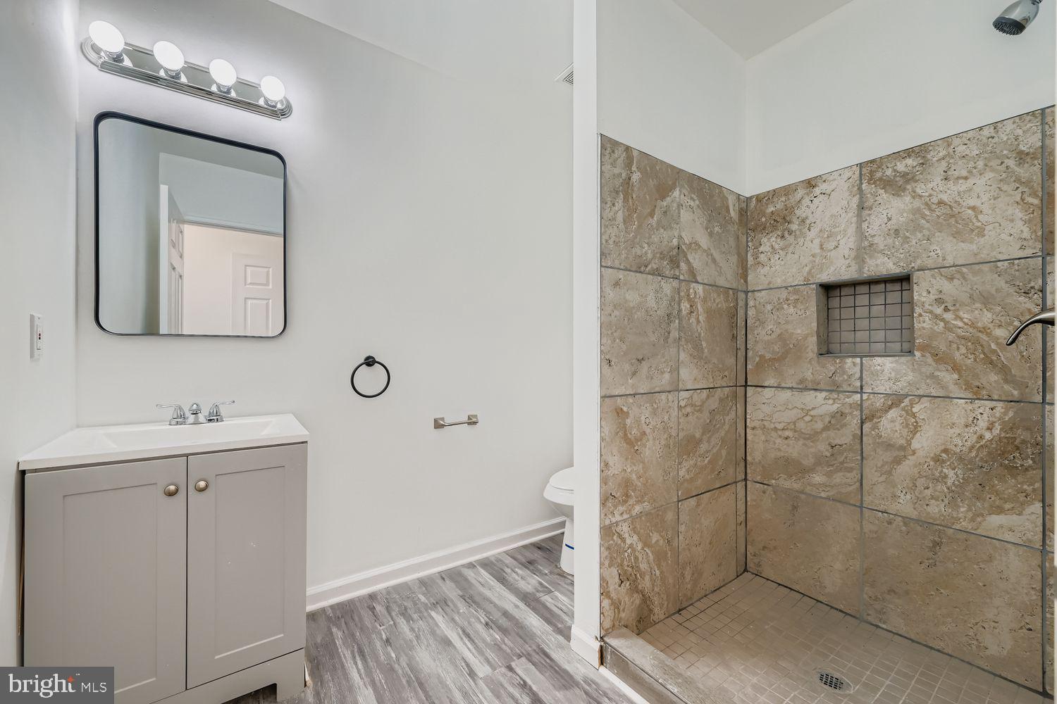 1006 East 20th Street Baltimore, MD 21218 - Photo 14 of 29 a bathroom with a mirror a shower and vanity
