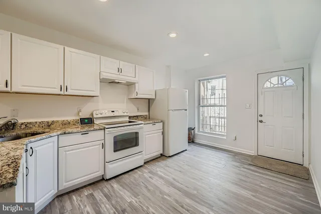 a kitchen with granite countertop white cabinets and white appliances