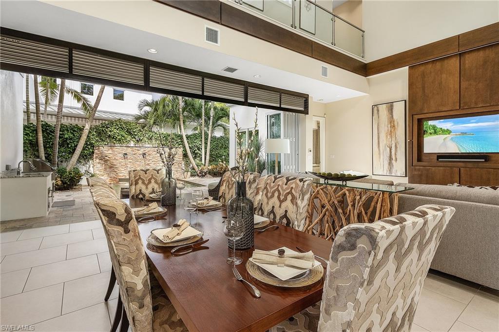 9149 Mercato Way Naples, FL 34108 - Photo 15 of 47 a dining room with furniture large windows and wooden floor