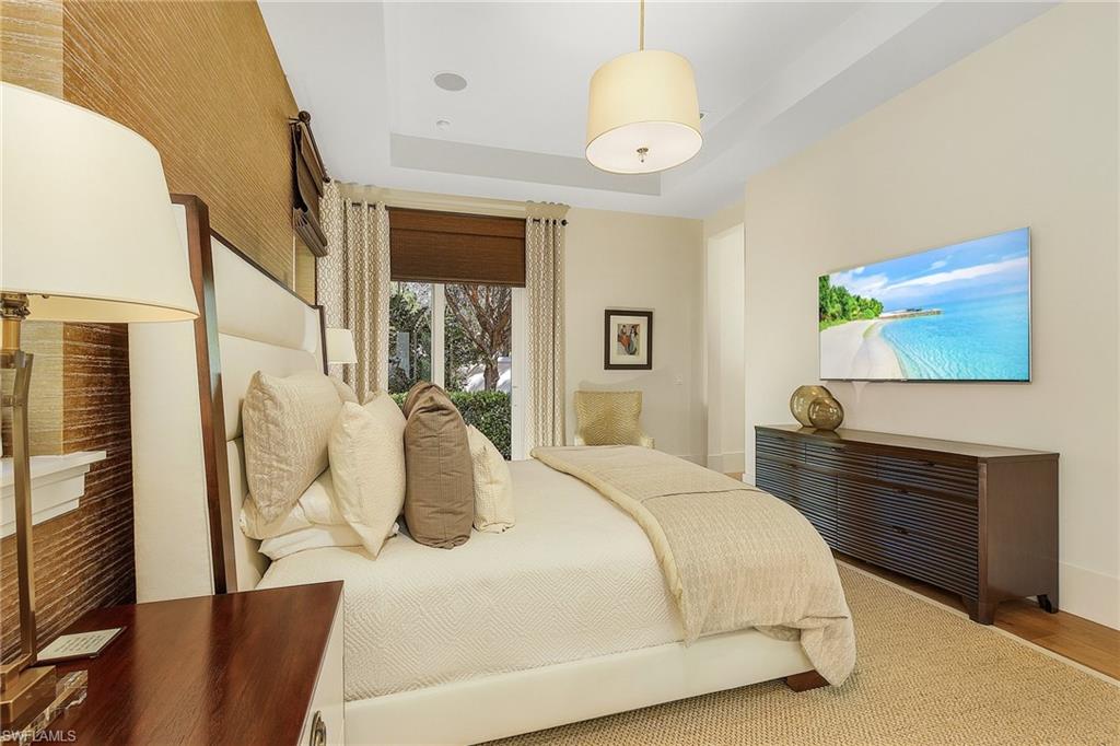 9149 Mercato Way Naples, FL 34108 - Photo 22 of 47 a bedroom with a large bed and a chandelier