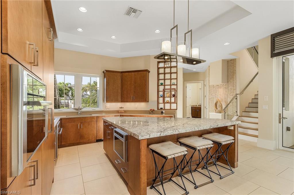 9149 Mercato Way Naples, FL 34108 - Photo 9 of 47 a kitchen with granite countertop a stove a sink a counter top space and living room view