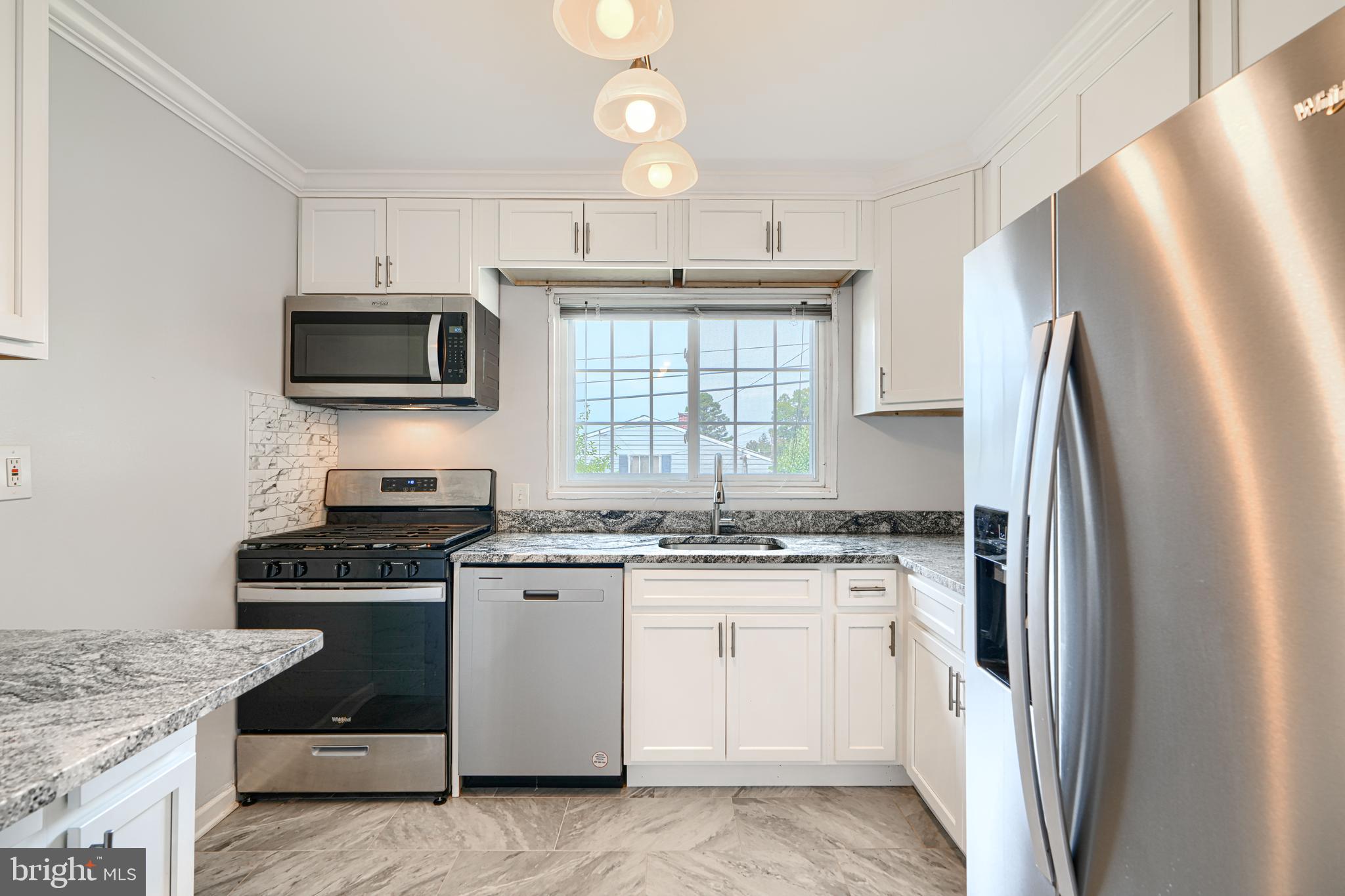 930 Sedgley Road Baltimore, MD 21228 - Photo 15 of 43 a kitchen with stainless steel appliances granite countertop a refrigerator a stove a sink a microwave and wooden cabinets