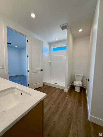 4956 North 925 East, Unit 87 Enoch, UT 84721 - Photo 12 of 19 Bathroom featuring wood-finish flooring, a white vanity with an integrated sink and light-colored countertop, a walk-in shower with white subway tile, a high transom window, and recessed lighting