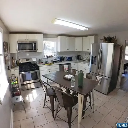 a kitchen with stainless steel appliances granite countertop a stove a sink dishwasher a microwave oven with a dining table and chair