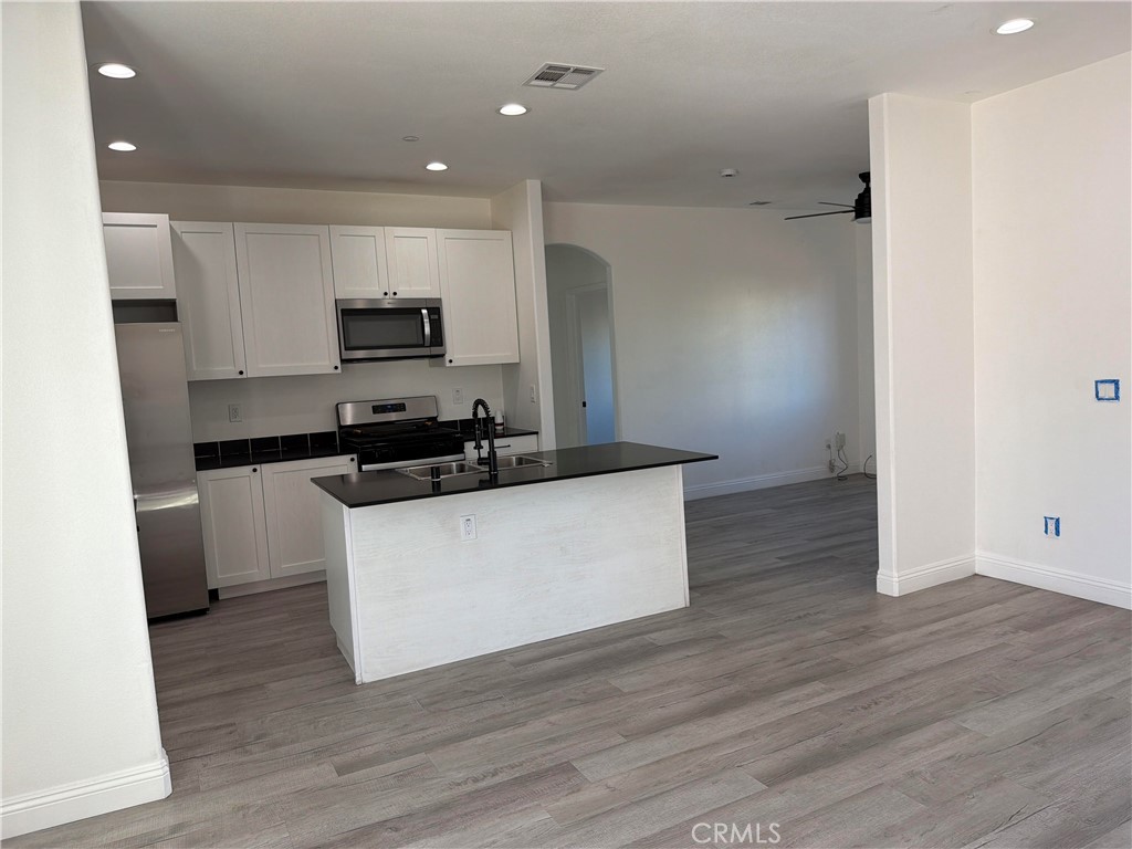 12690 7th Street Yucaipa, CA 92399 - Photo 3 of 7 a kitchen with kitchen island a sink a stove a microwave and wooden floor