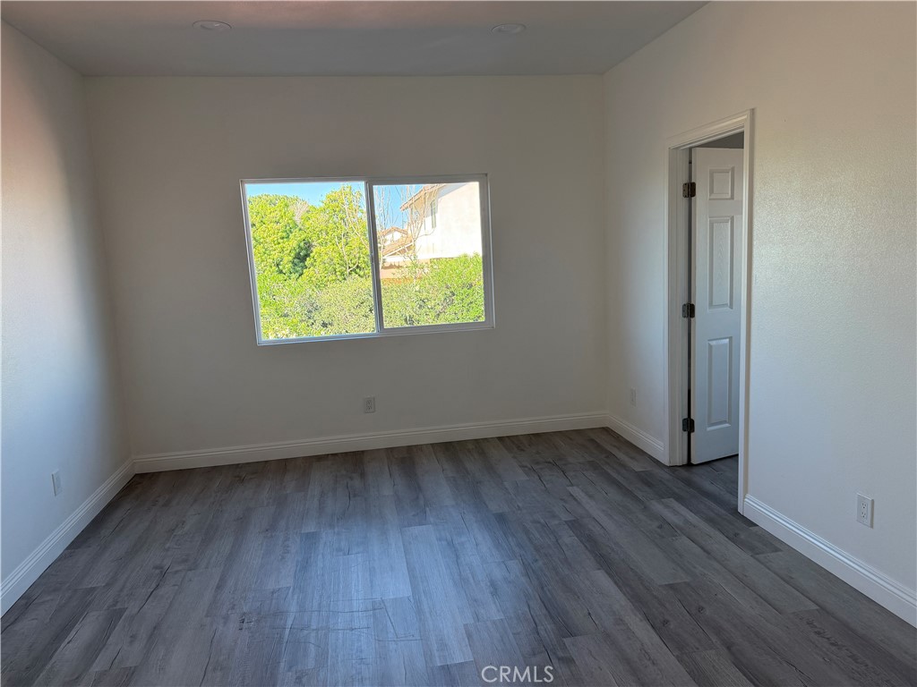 12690 7th Street Yucaipa, CA 92399 - Photo 5 of 7 an empty room with wooden floor and a window