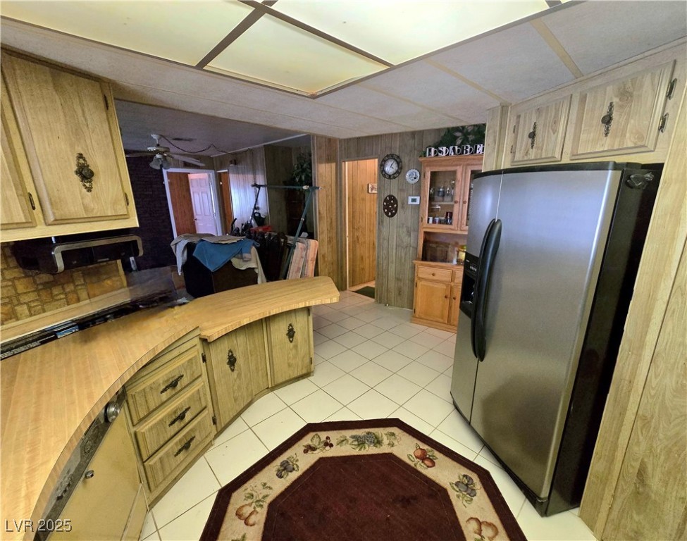 2321 West Simkins Road Pahrump, NV 89060 - Photo 10 of 80 Kitchen featuring stainless steel refrigerator with ice dispenser, a peninsula, light tile patterned flooring, light countertops, and ceiling fan