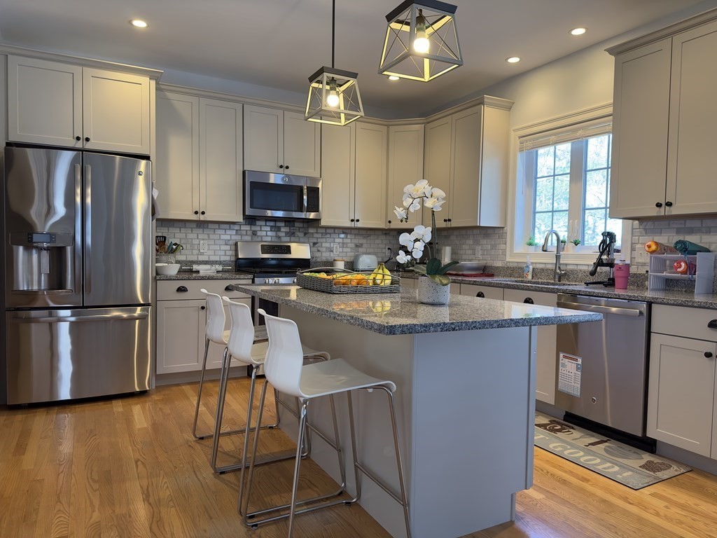 47 Quarry Road, Unit 47 Acton, MA 01720 - Photo 2 of 15 a kitchen with granite countertop a refrigerator a sink dishwasher a stove top oven a kitchen island and chairs with wooden floor