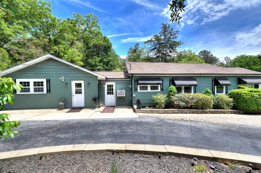 This charming home offers a welcoming facade with lush landscaping and awnings for comfort.