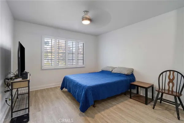a bedroom with a bed windows and a flat screen tv