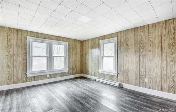 an empty room with wooden floor and windows with curtains