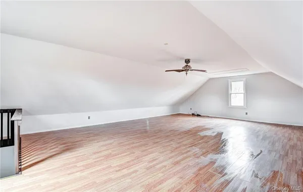 an empty room with wooden floor ceiling fan and windows