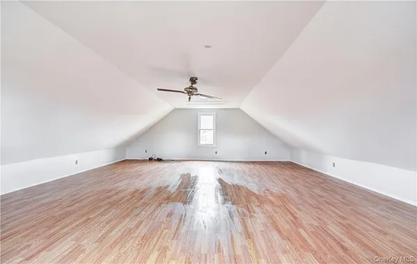 an empty room with wooden floor ceiling fan and windows