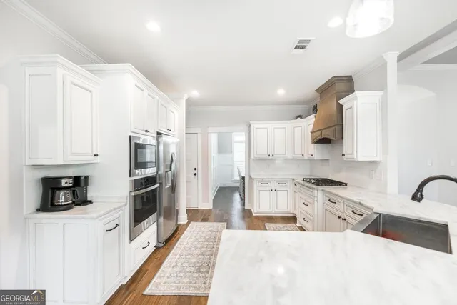 a large kitchen with stainless steel appliances kitchen island granite countertop a refrigerator and a stove top oven