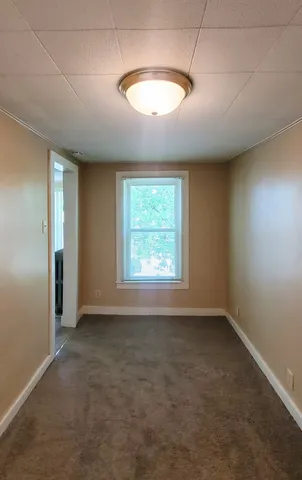 an empty room with a window and chandelier fan