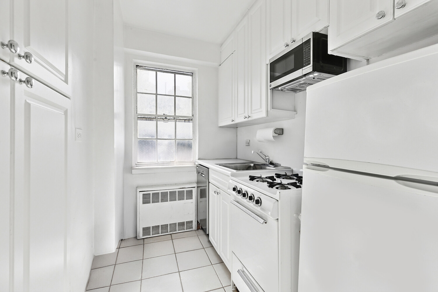 245 East 35th Street, Unit 4H Manhattan, NY 10016 - Photo 4 of 5 a kitchen with white cabinets and white appliances