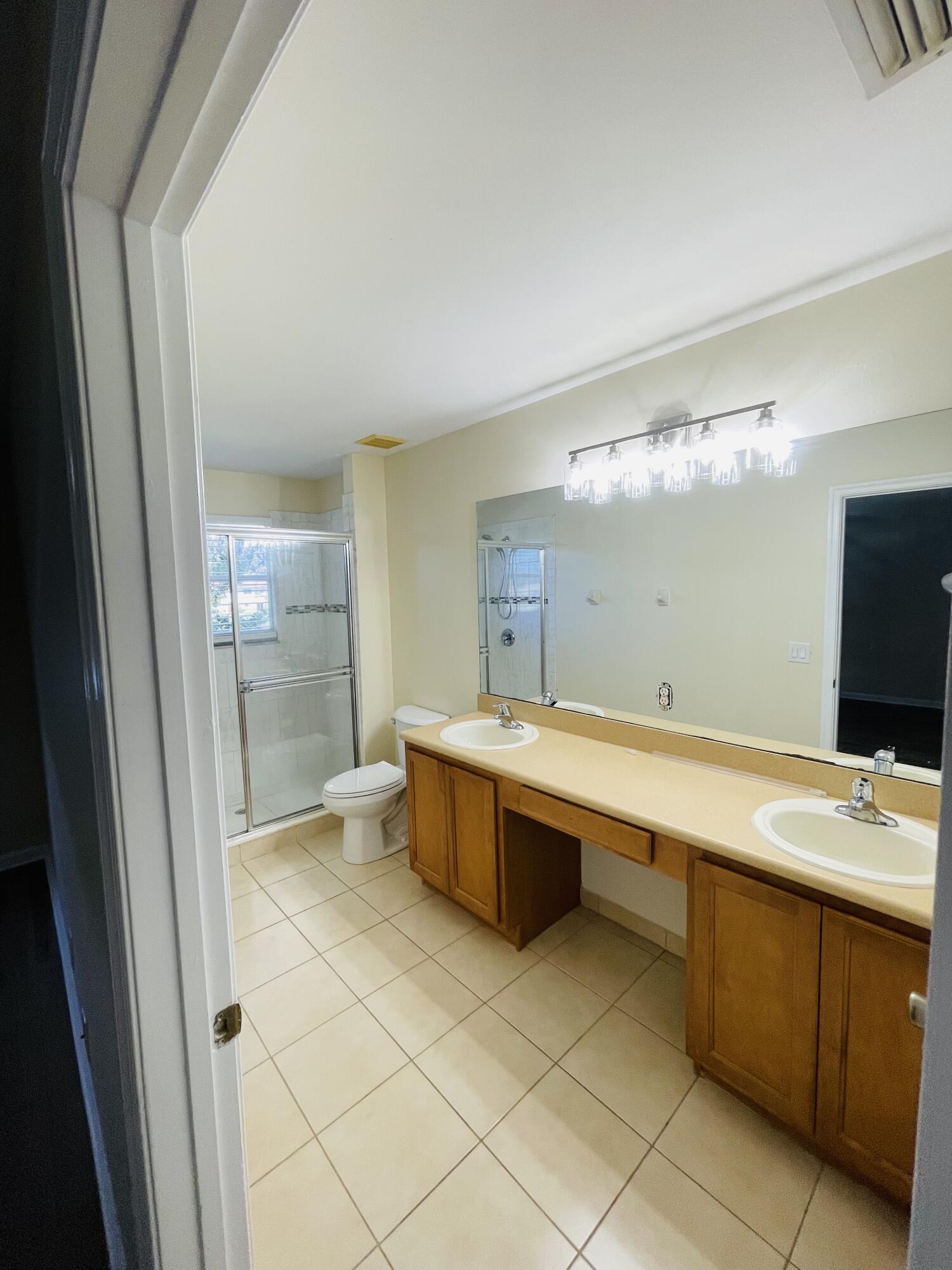 1146 Imperial Lake Road Lake Belvedere Estates, FL 33413 - Photo 16 of 20 a large bathroom with a double vanity sink toilet and mirror