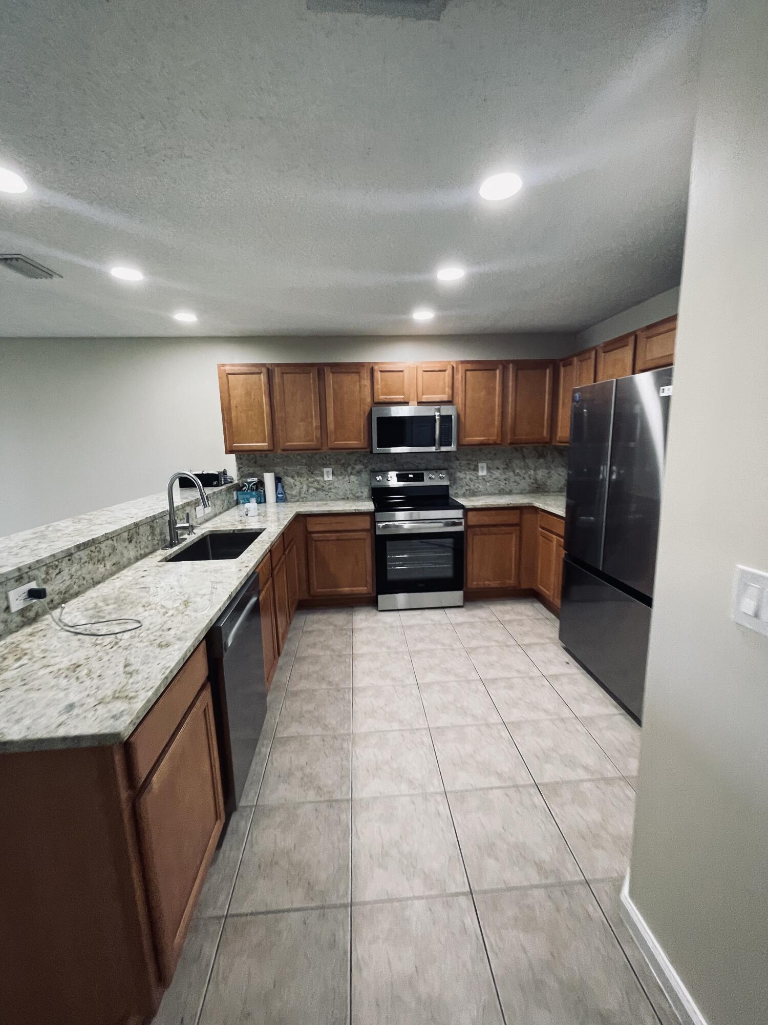 1146 Imperial Lake Road Lake Belvedere Estates, FL 33413 - Photo 5 of 20 a kitchen with stainless steel appliances granite countertop a sink stove and cabinets