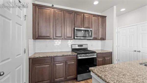 a kitchen with kitchen island granite countertop a sink cabinets and stainless steel appliances