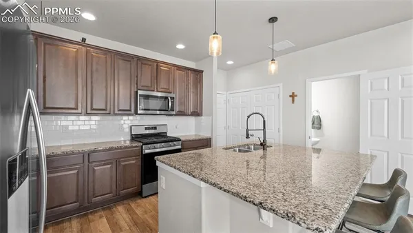a kitchen with kitchen island granite countertop a sink stainless steel appliances and white cabinets