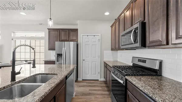 a kitchen with granite countertop stainless steel appliances window a refrigerator and a sink