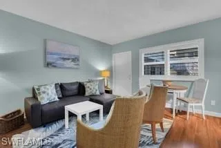 a living room with furniture wooden floor and kitchen view